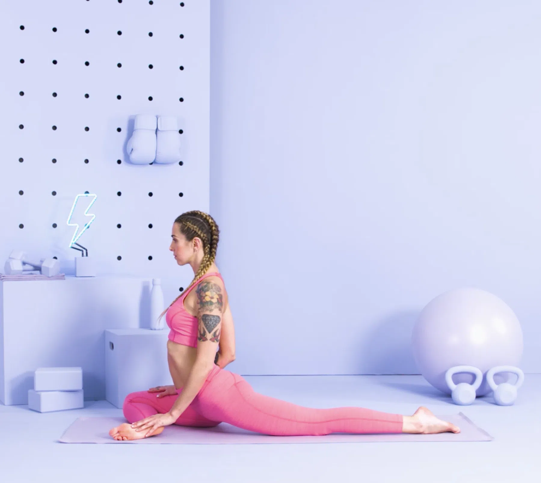 Vrouw doet pigeon pose met een been voor zich gevouwen en de ander gestrekt achter zich op een yogamatje.